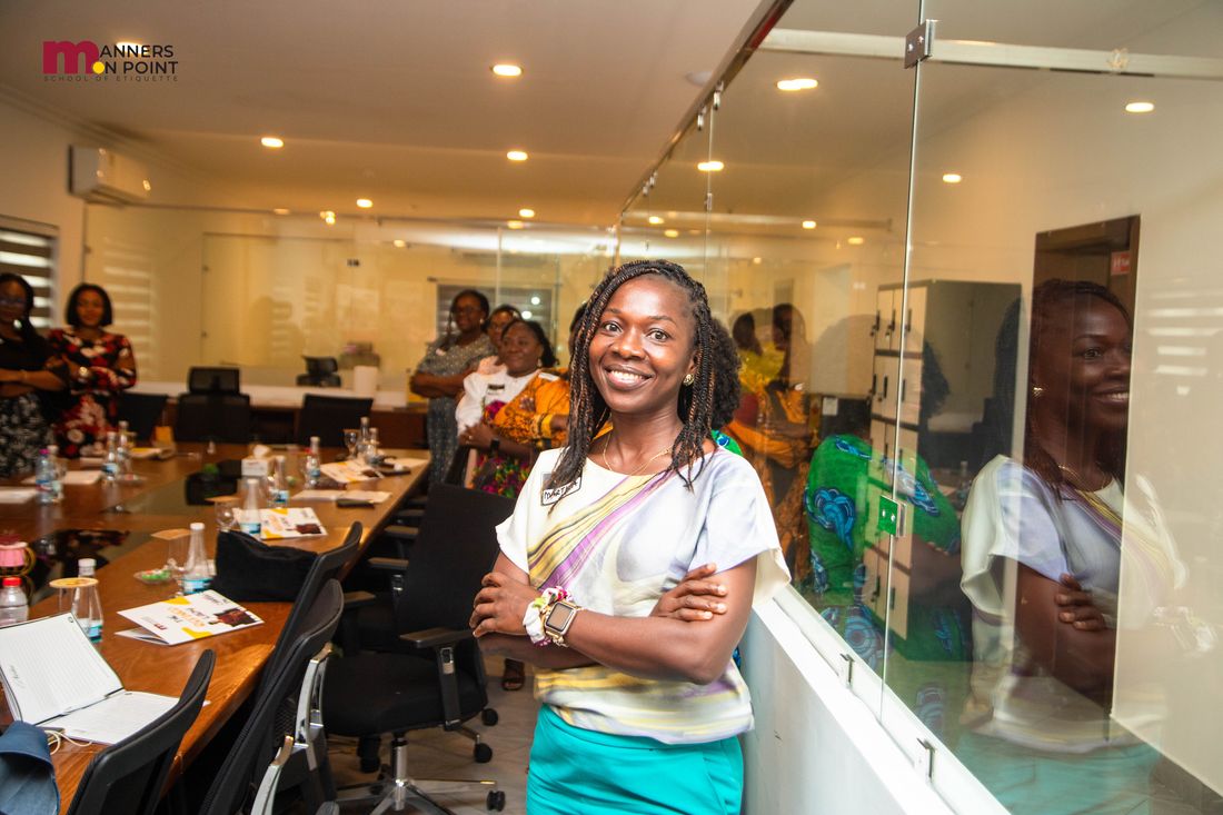 A participant standing confidently at the studio, arms folded, with the session under way behind her.