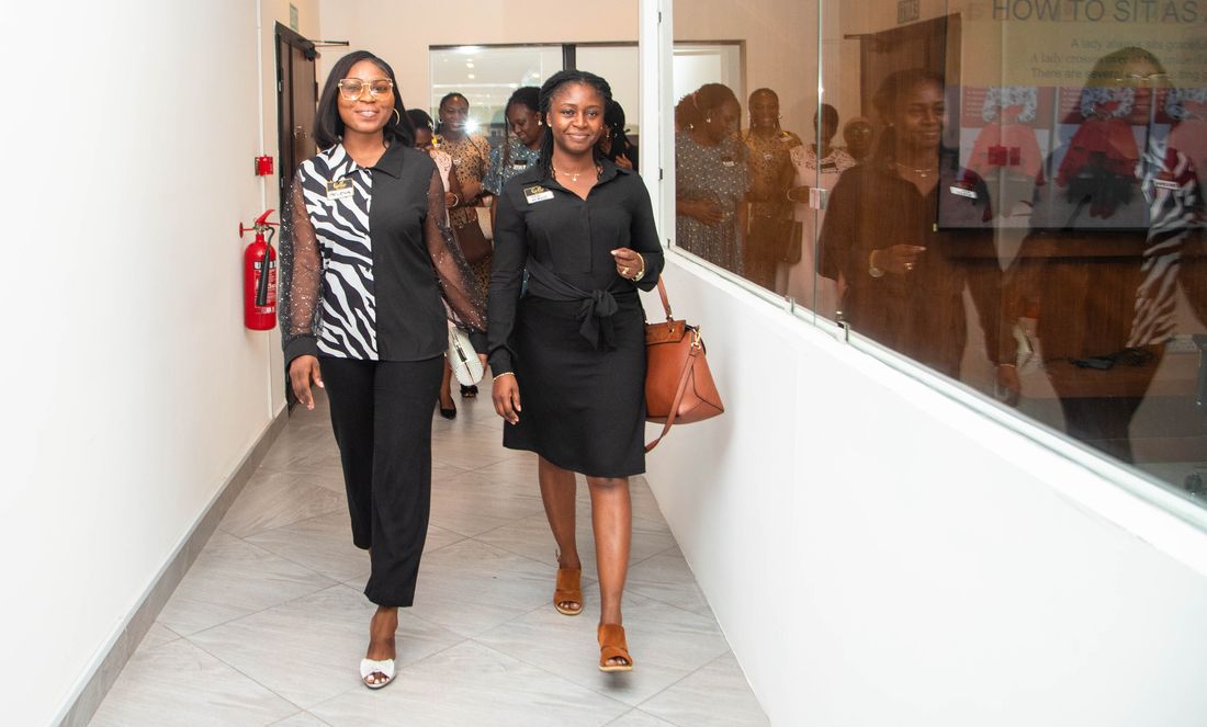 Two participants practising a graceful walk along the studio corridor.
